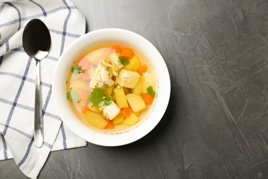 Photo of Homemade chicken soup served on grey table, top view with space for text