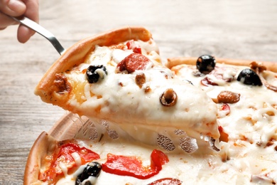 Woman holding shovel with slice of delicious hot pizza over table, closeup