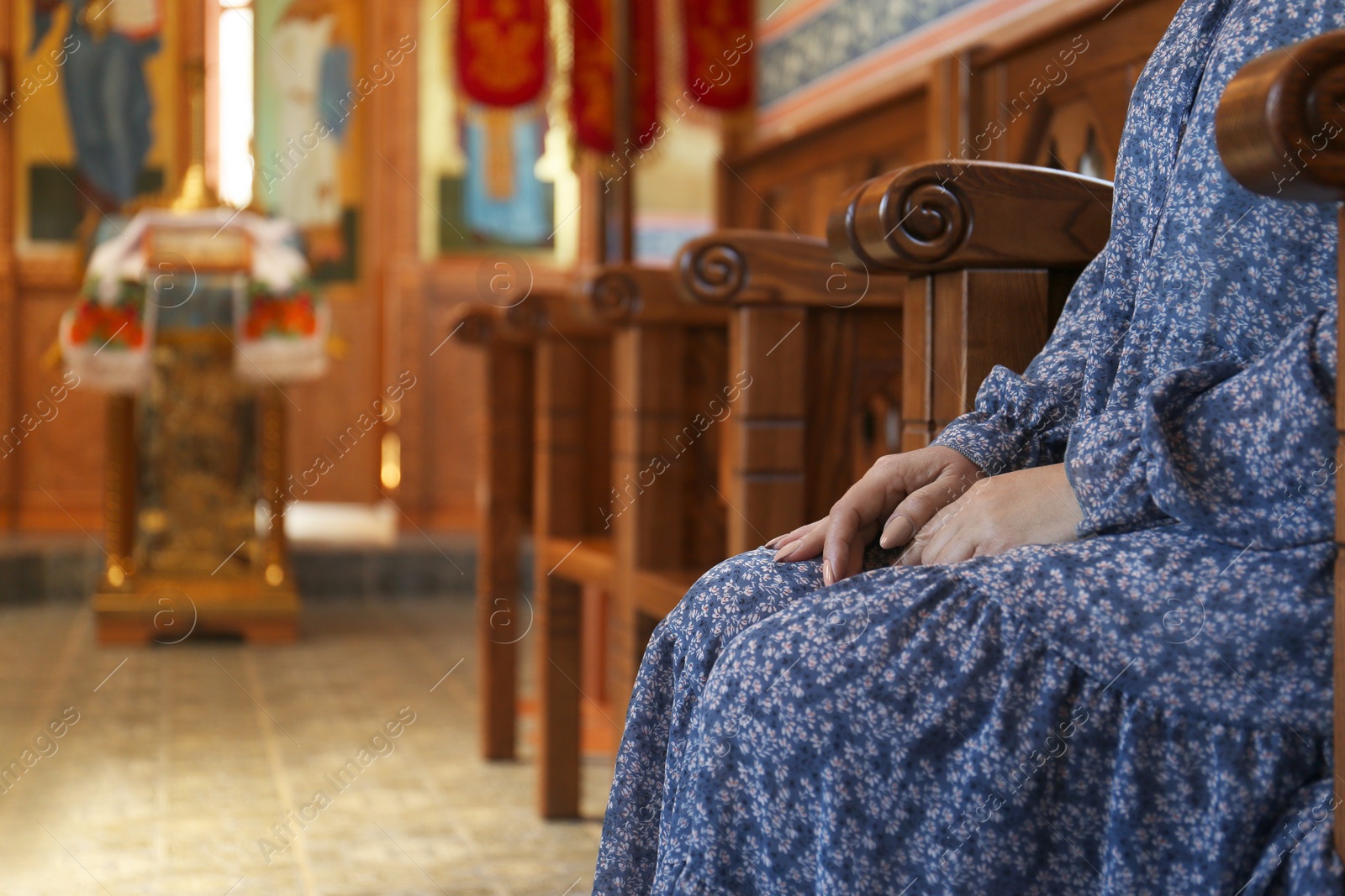 Photo of Mature woman sitting on wooden bench in church, closeup. Space for text