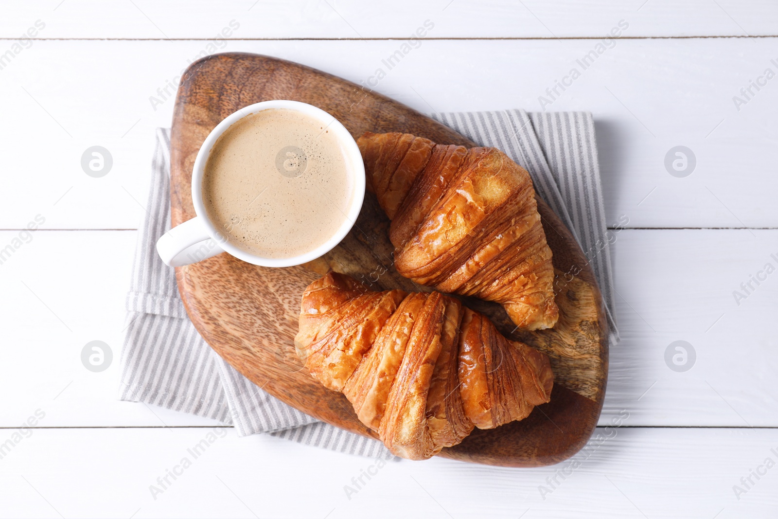 Photo of Tasty breakfast. Cup of coffee and croissants on white wooden table, top view