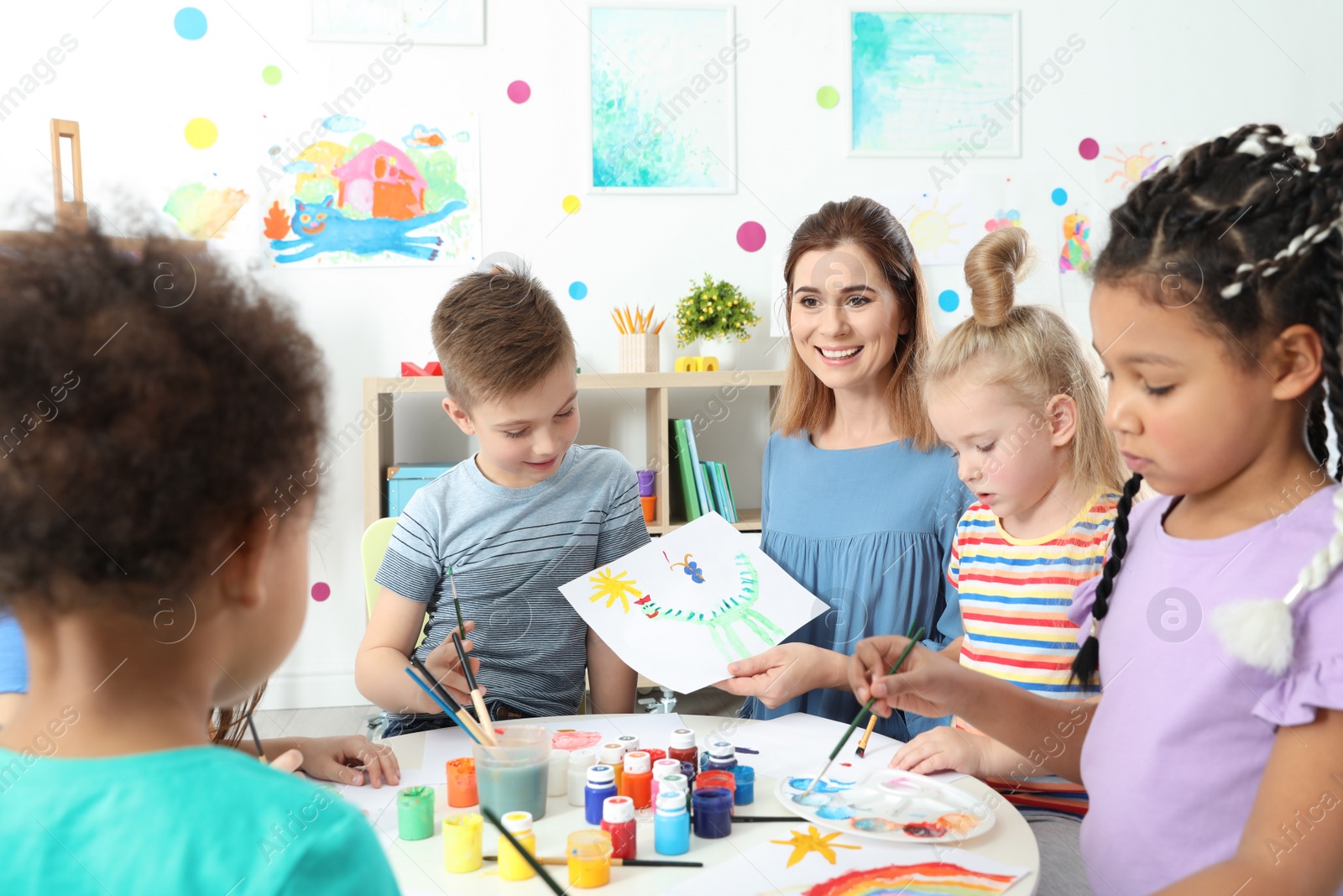 Photo of Children with female teacher at painting lesson indoors