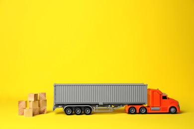 Photo of Toy truck and wooden cubes on yellow background, space for text. Export concept