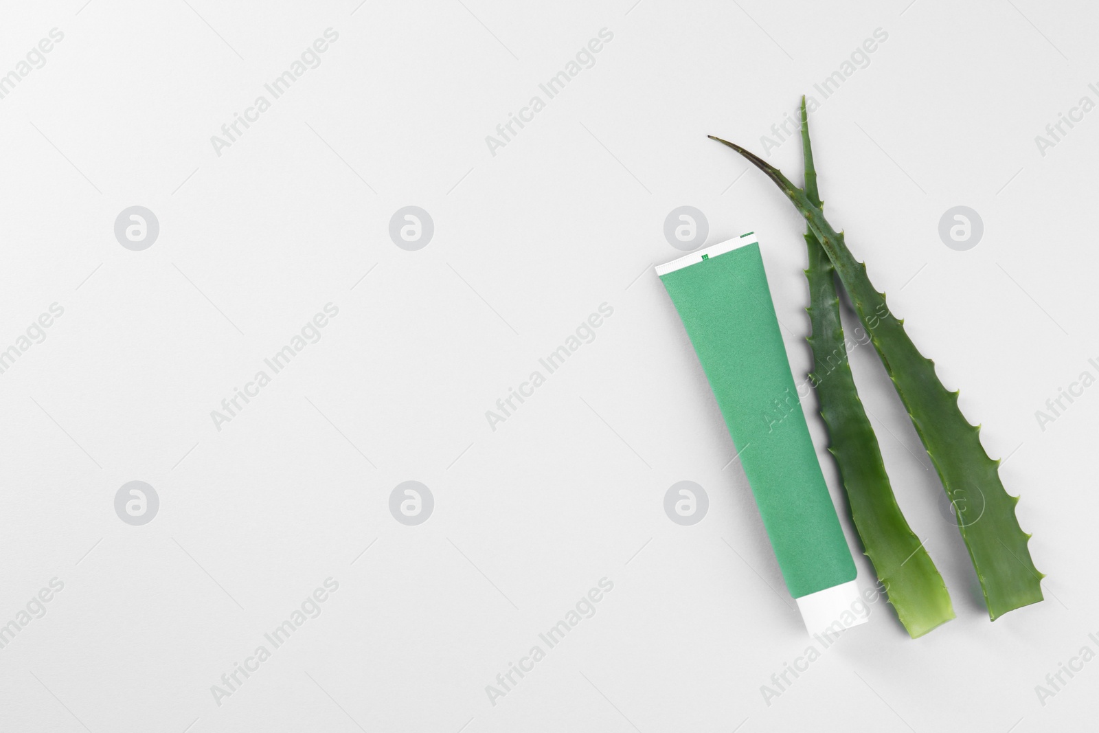 Photo of Tube of toothpaste and fresh aloe on white background, top view