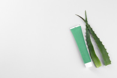 Tube of toothpaste and fresh aloe on white background, top view