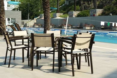 Photo of Many chairs and table near outdoors swimming pool at resort