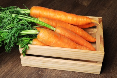 Tasty ripe carrots in crate on wooden table
