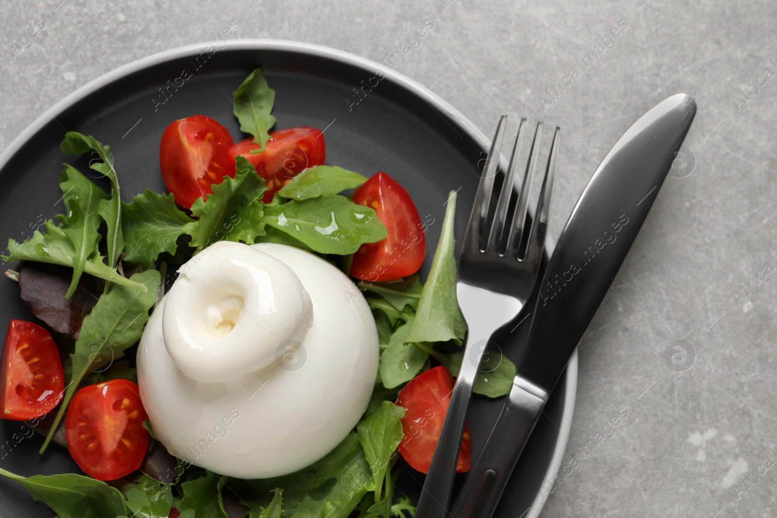 Photo of Delicious burrata salad with tomatoes and arugula served on grey table, top view