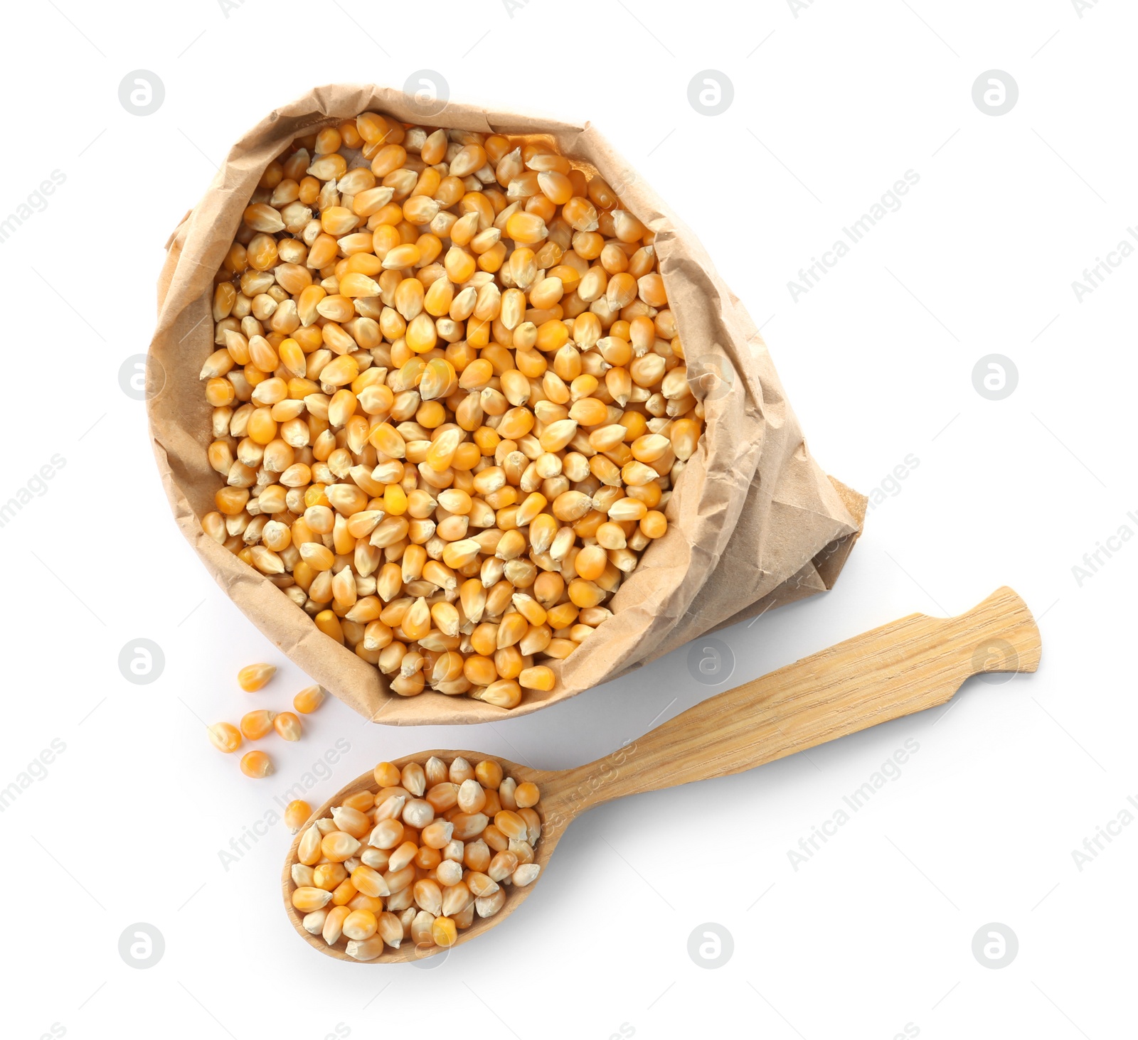 Photo of Paper bag and spoon with raw corn kernels on white background. Healthy grains and cereals