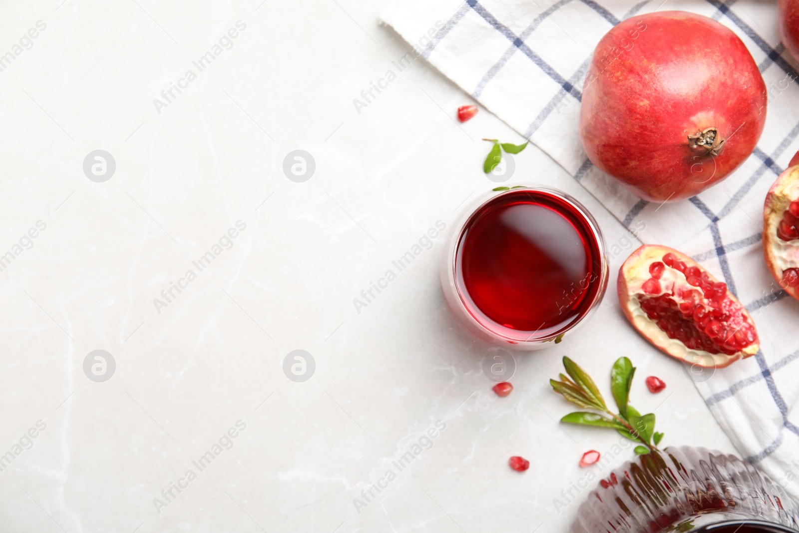 Photo of Glass of pomegranate juice and fresh fruits on white marble table, flat lay. Space for text