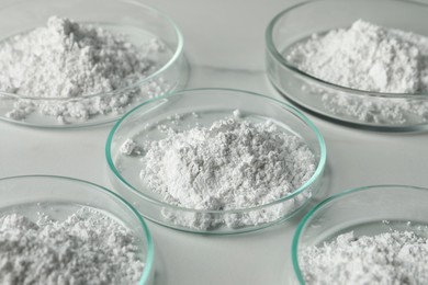 Photo of Petri dishes with calcium carbonate powder on white marble table, closeup