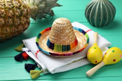 Photo of Mexican sombrero hat, maracas and poncho on turquoise wooden table