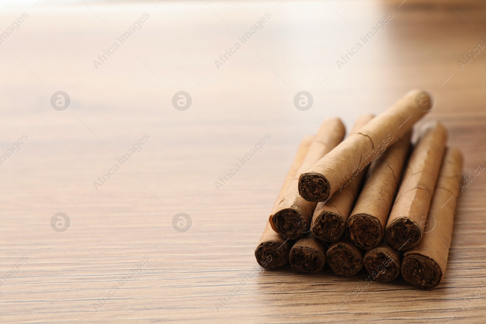 Photo of Many cigars on wooden table, space for text