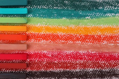 Photo of Colorful pastel chalks on abstract painting, flat lay. Drawing materials