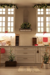 Photo of Small Christmas trees and festive decor in kitchen