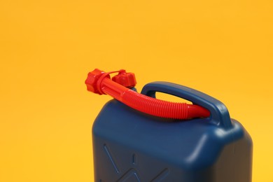 Photo of Blue plastic canister with tube on orange background, closeup. Space for text