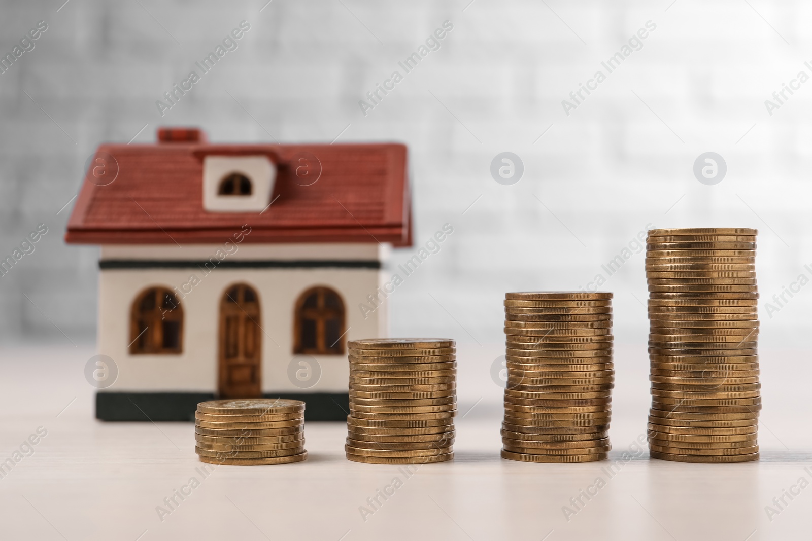 Photo of Mortgage. Stacked coins and house model on light table