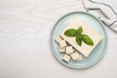 Delicious tofu with basil on white wooden table, top view. Space for text