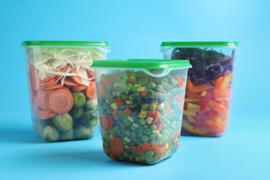 Set of plastic containers with fresh food on light blue background