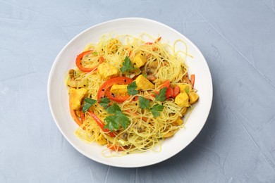 Stir-fry. Delicious cooked noodles with chicken and vegetables in bowl on gray table, top view