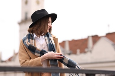 Beautiful woman in warm scarf and hat outdoors, space for text