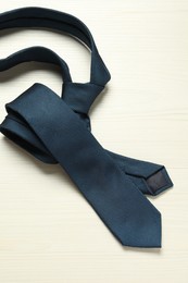 Photo of One blue necktie on white wooden table, top view