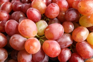 Fresh ripe juicy pink grapes as background, closeup view