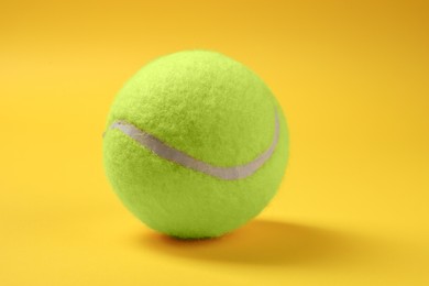 Photo of One bright tennis ball on yellow background