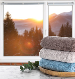 Image of Fresh towels on marble table and window with beautiful view indoors