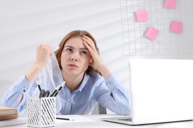 Angry woman popping bubble wrap at desk in office. Stress relief