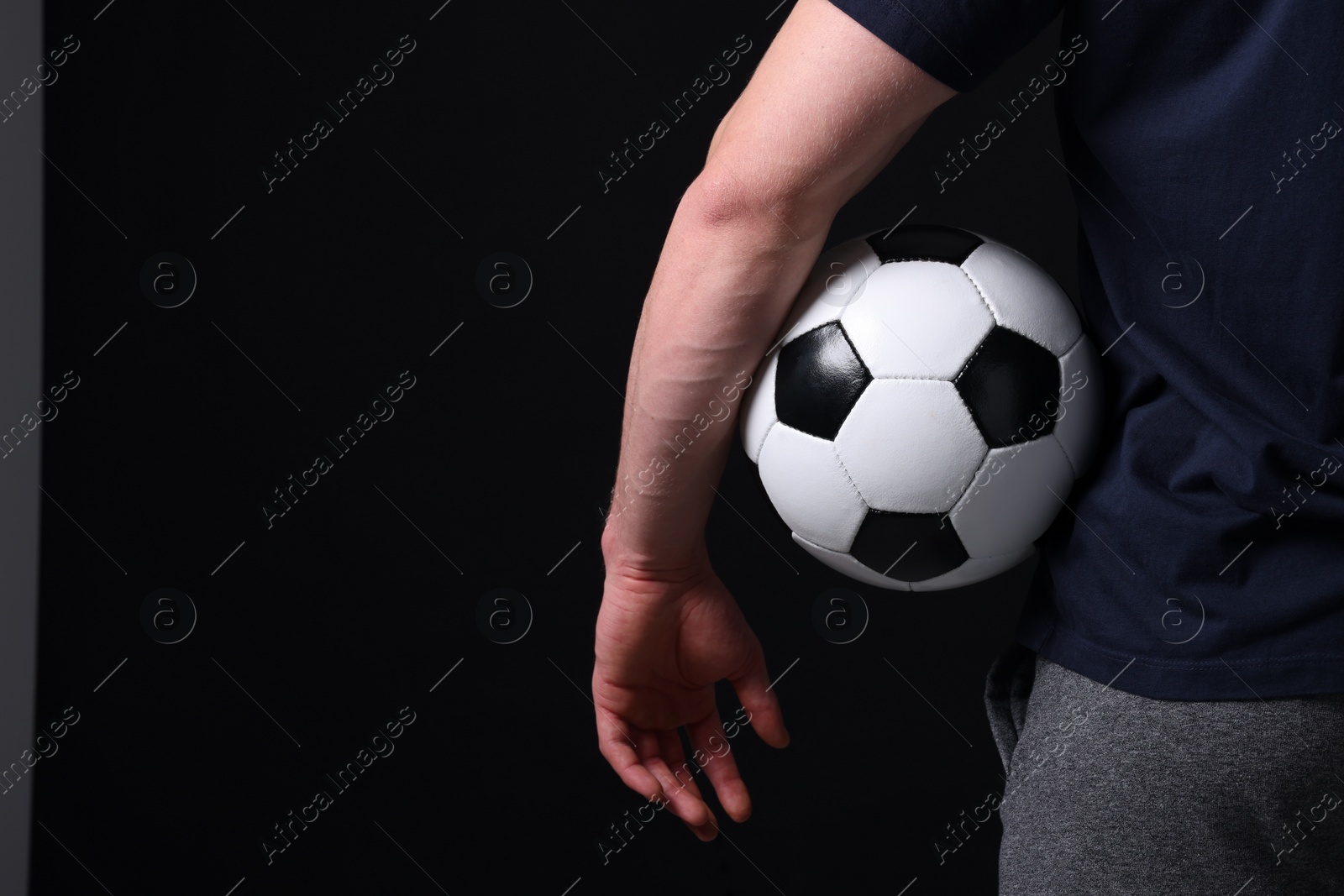 Photo of Athletic man with soccer ball on black background, closeup. Space for text