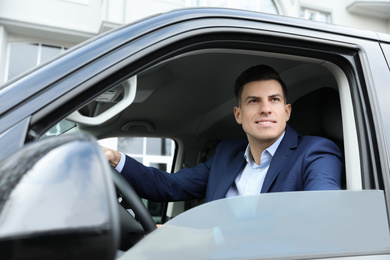 Handsome man driving his modern car, view from outside