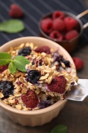 Photo of Eating tasty baked oatmeal with berries at table, closeup