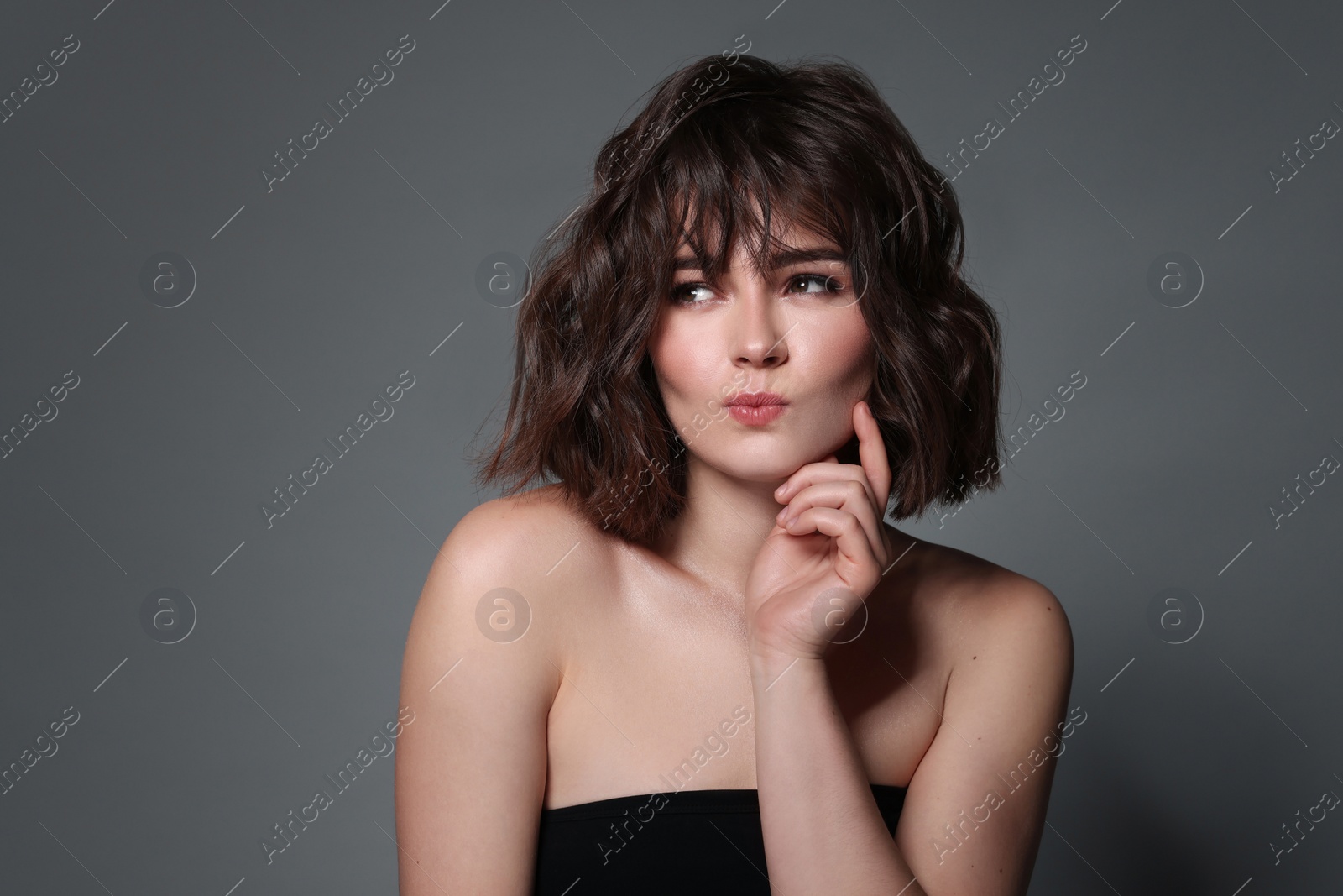 Photo of Portrait of beautiful young woman with wavy hairstyle on grey background