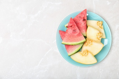 Flat lay composition with tasty sliced melon and watermelon on light background. Space for text