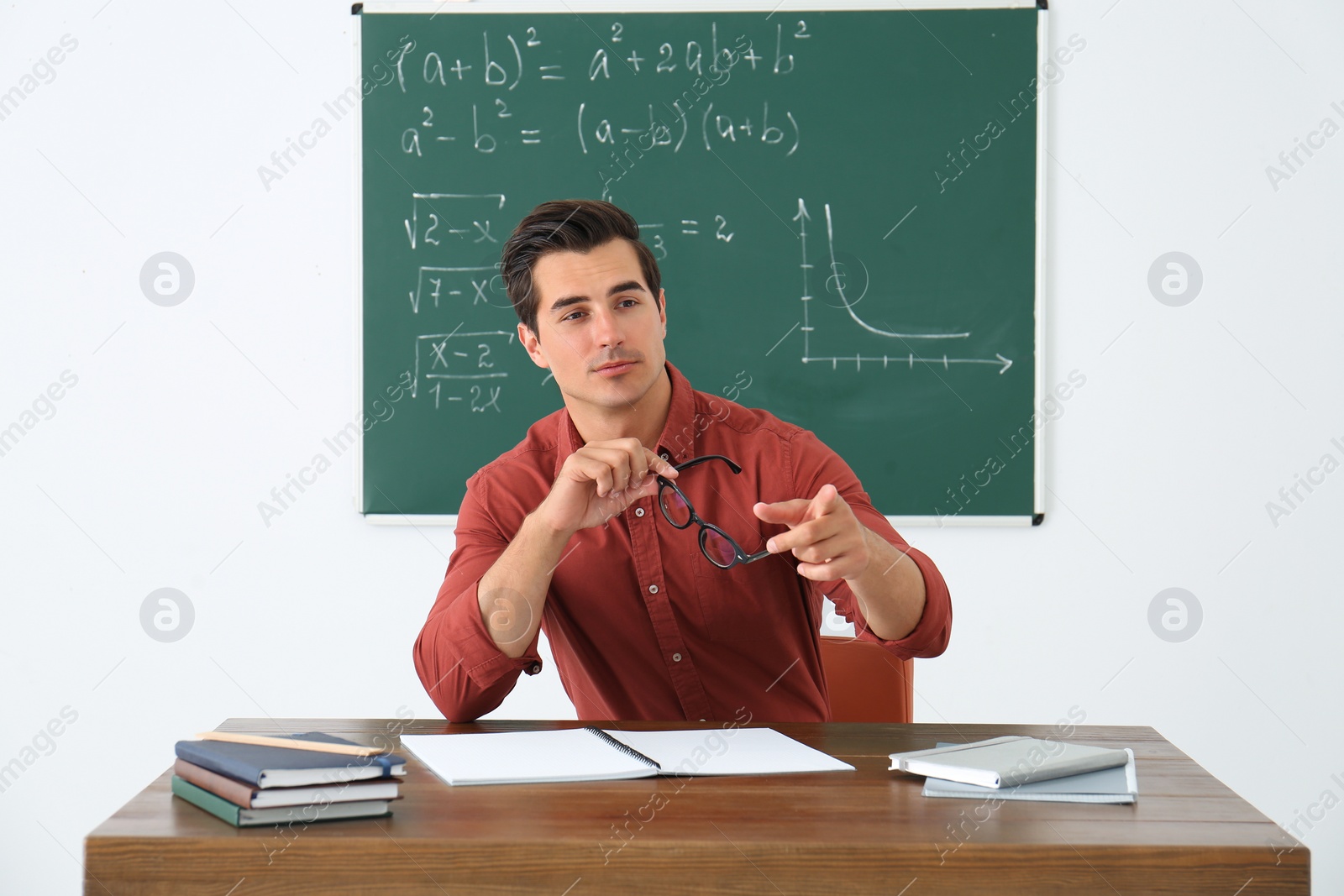 Photo of Young teacher working at table in classroom