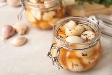 Photo of Preserved garlic in glass jar on table, closeup. Space for text