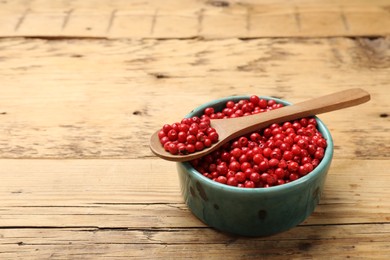 Photo of Aromatic spice. Red pepper in bowl and spoon on wooden table, closeup. Space for text