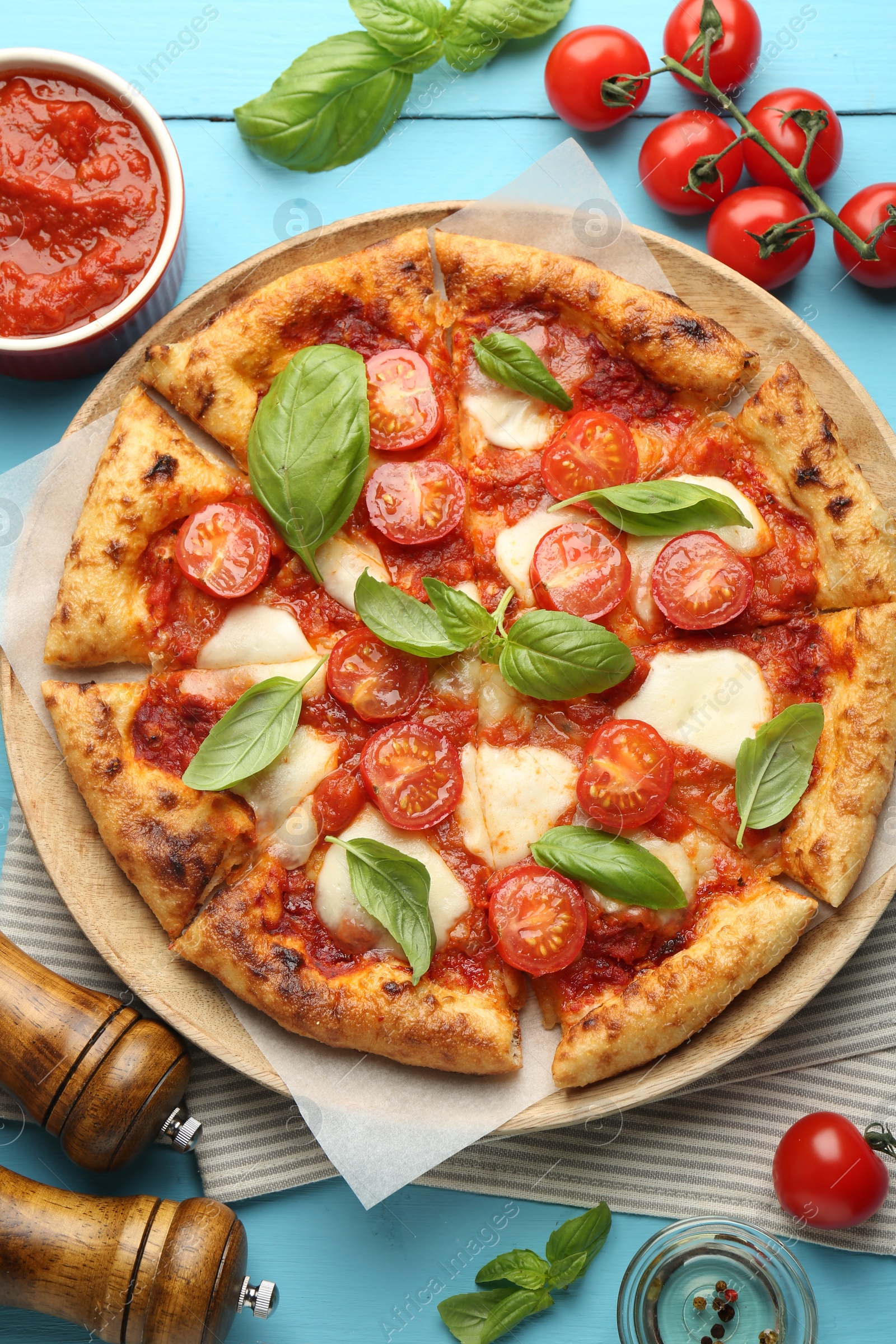 Photo of Delicious Margherita pizza and ingredients on light blue wooden table, top view