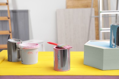 Pink paint and brush on yellow table indoors