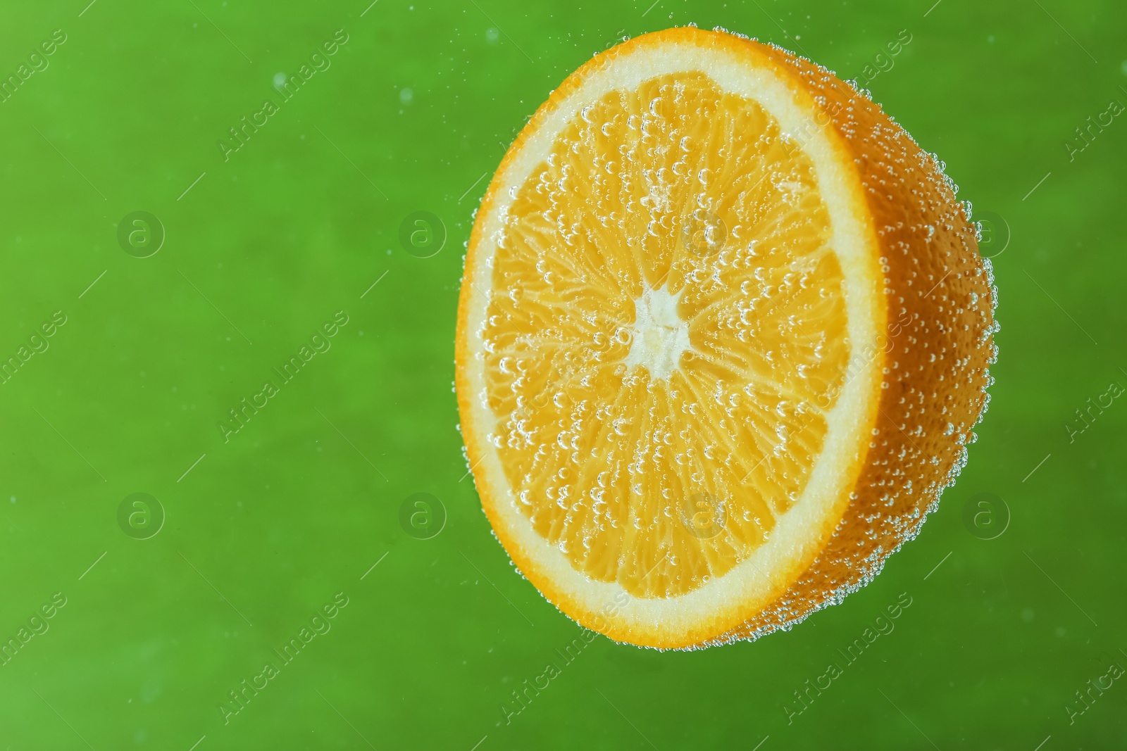 Photo of Half of orange in sparkling water on green background. Citrus soda