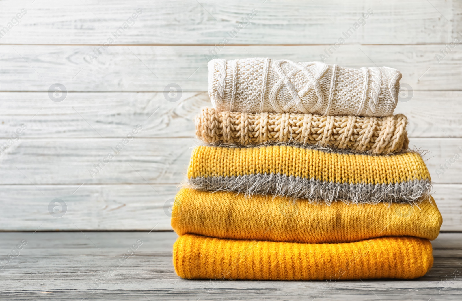 Photo of Stack of warm knitted clothes on table