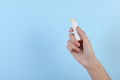 Photo of Woman with lip balm on light blue background, closeup. Space for text