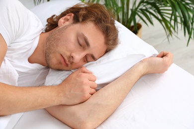 Handsome young man sleeping on pillow in morning. Bedtime