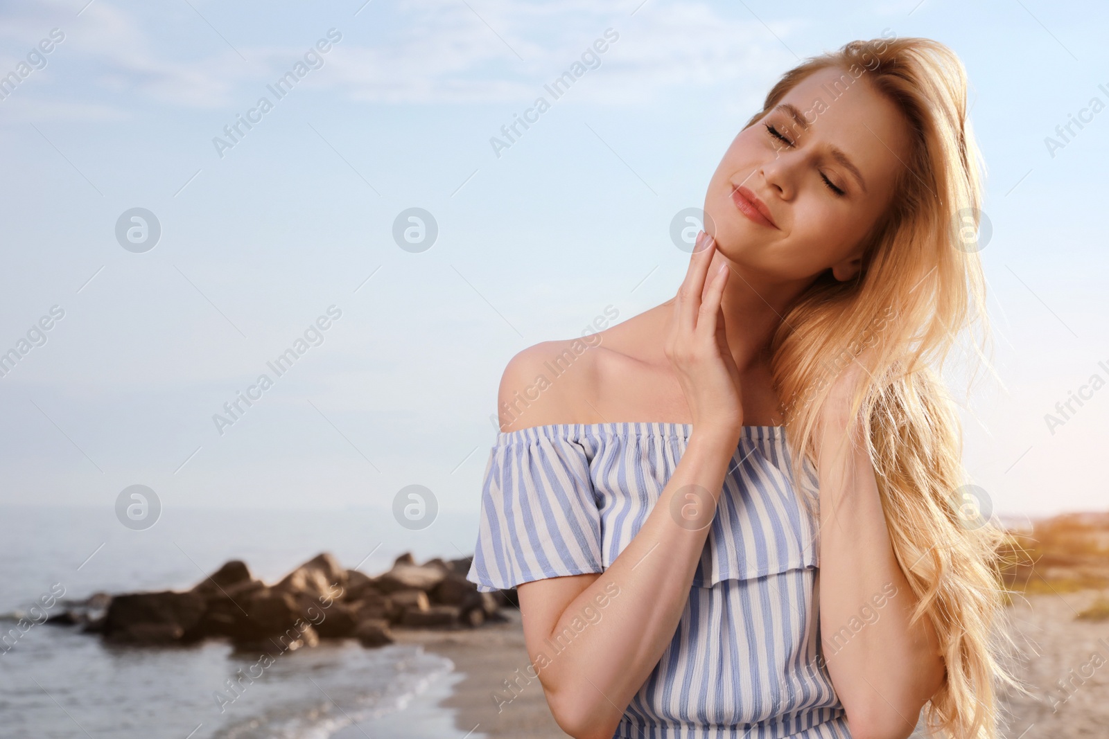 Photo of Beautiful young woman near sea on sunny day, space for text