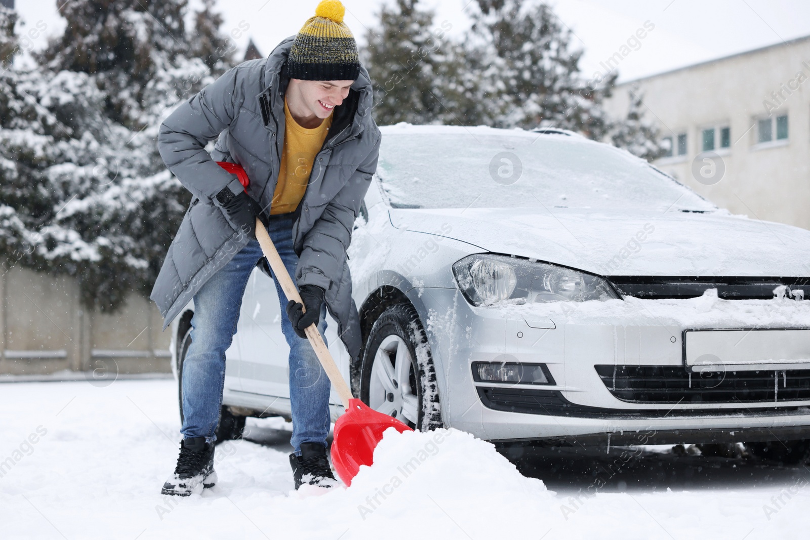 Photo of Man removing snow with shovel near car outdoors