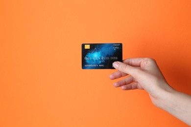 Photo of Woman holding credit card on orange background, closeup