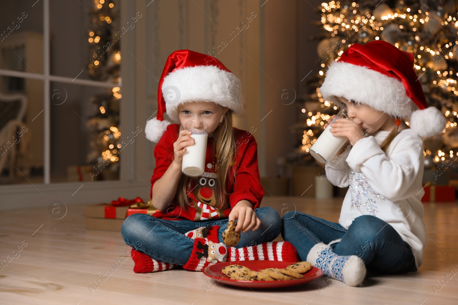 Photo of Cute little children drinking milk in living room. Christmas time