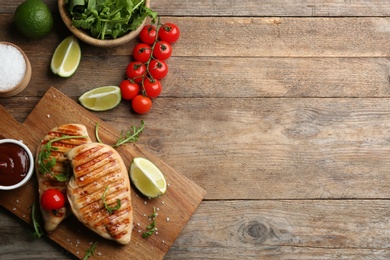 Flat lay composition tasty grilled chicken fillets on wooden table. Space for text