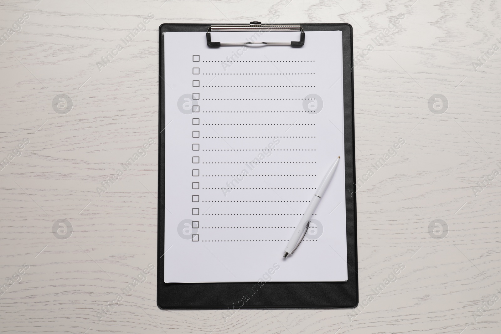 Photo of Clipboard with checkboxes and pen on wooden table, top view