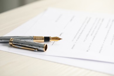 Photo of Fountain pen and documents on wooden table. Notary services